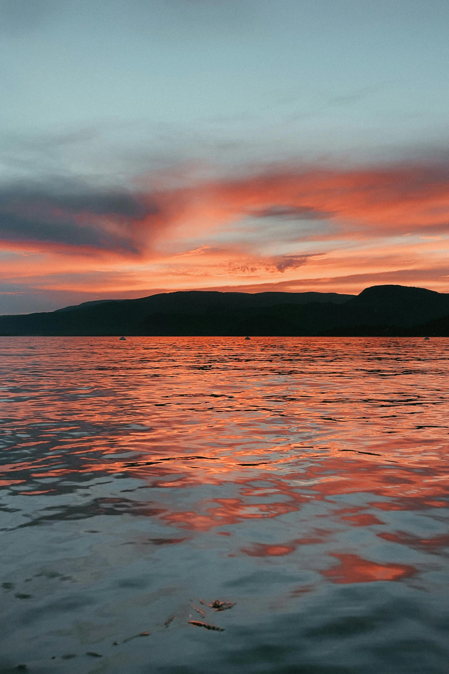 the sky is pink and orange with waves on the water