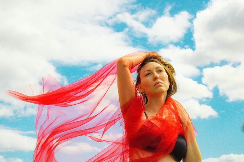 a girl in a red bikini standing under clouds