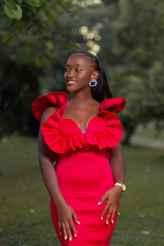 a woman wearing a red gown standing in the grass