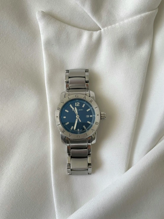 a rolex watch is laying on a white fabric