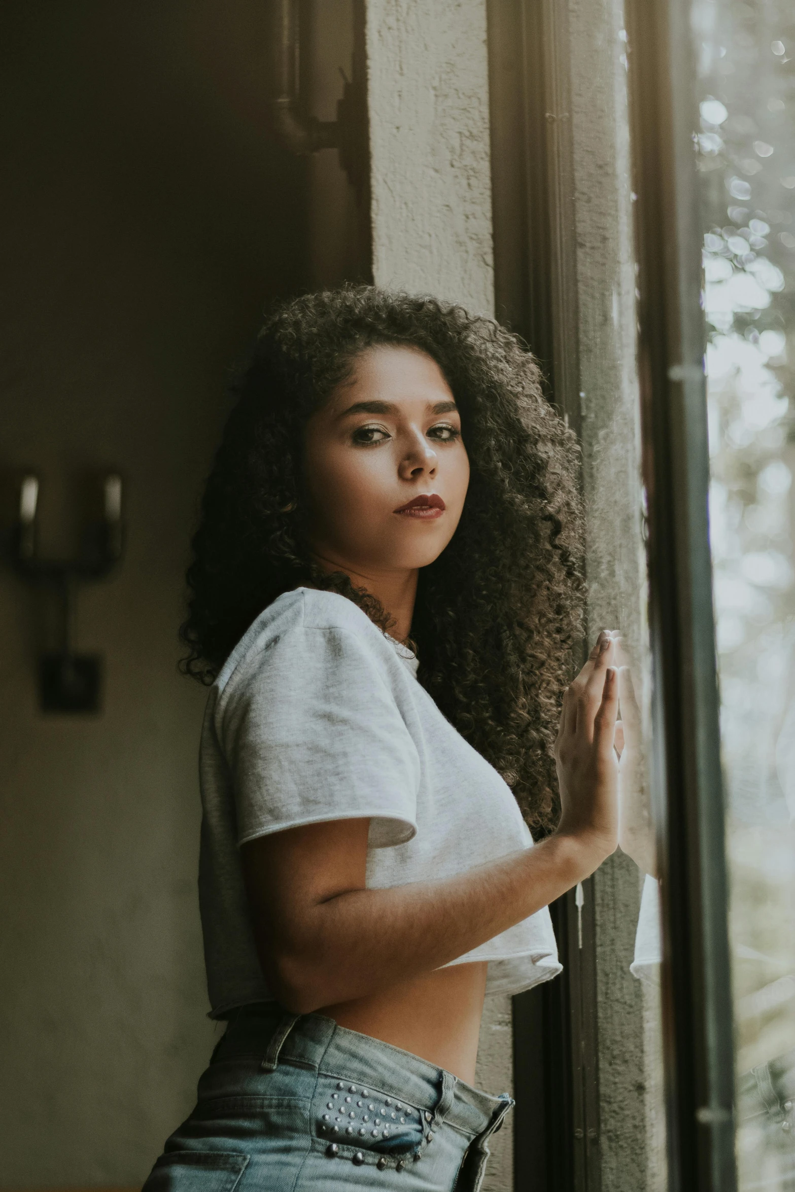 a person in a shirt and jeans near a window