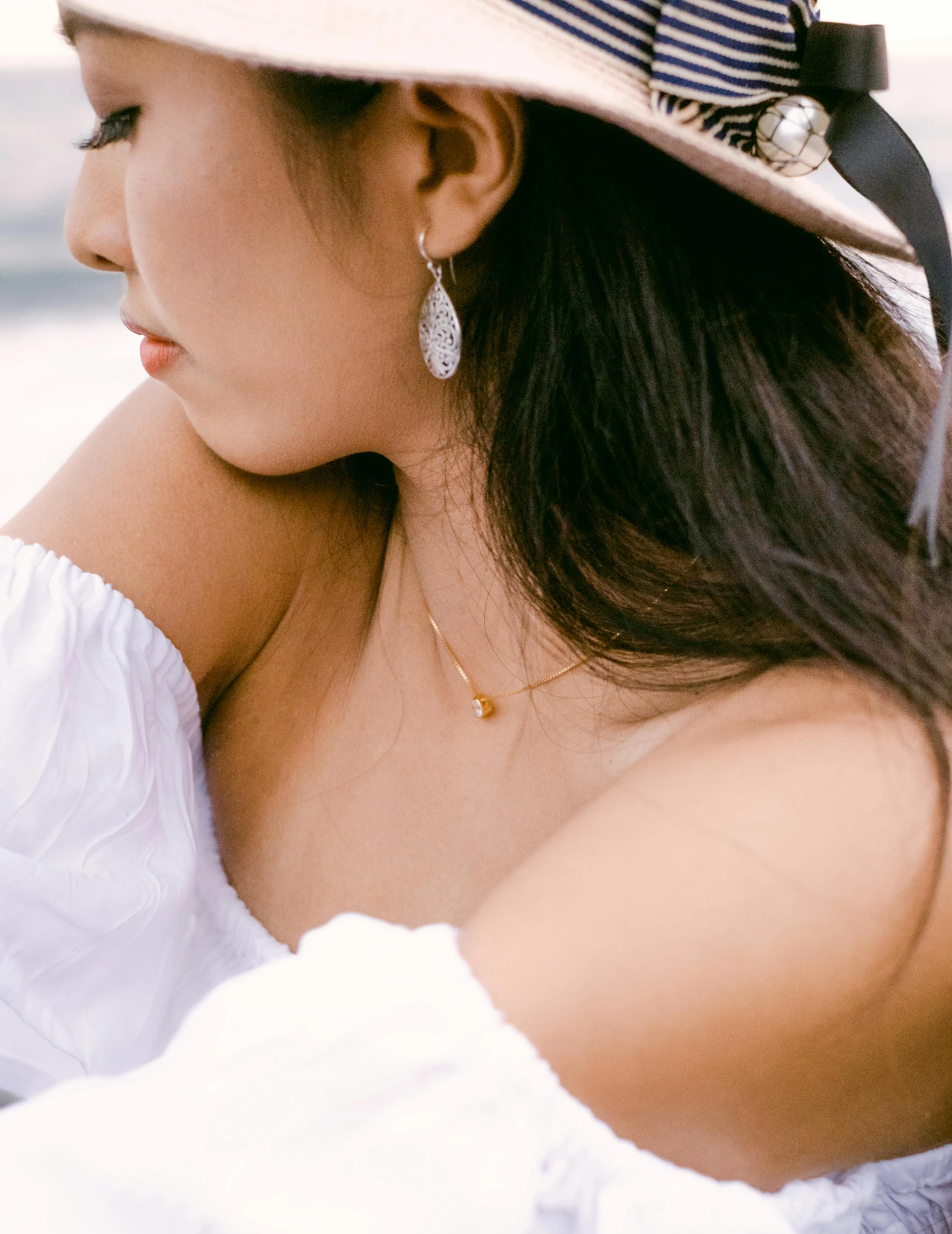 a woman in a white dress wears a blue and white hat