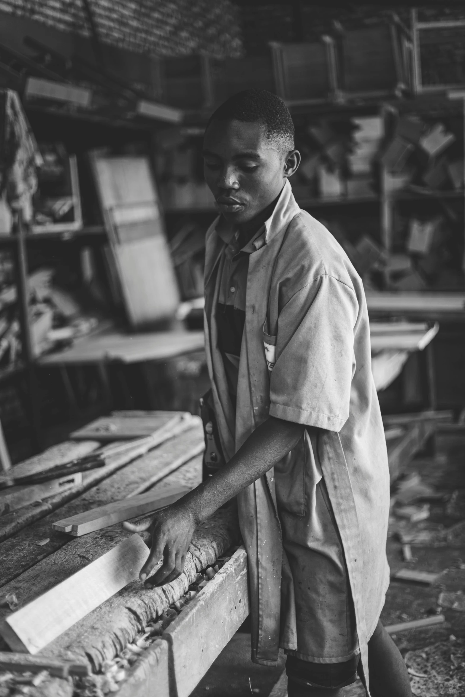 the young man stands behind a work bench in a shop