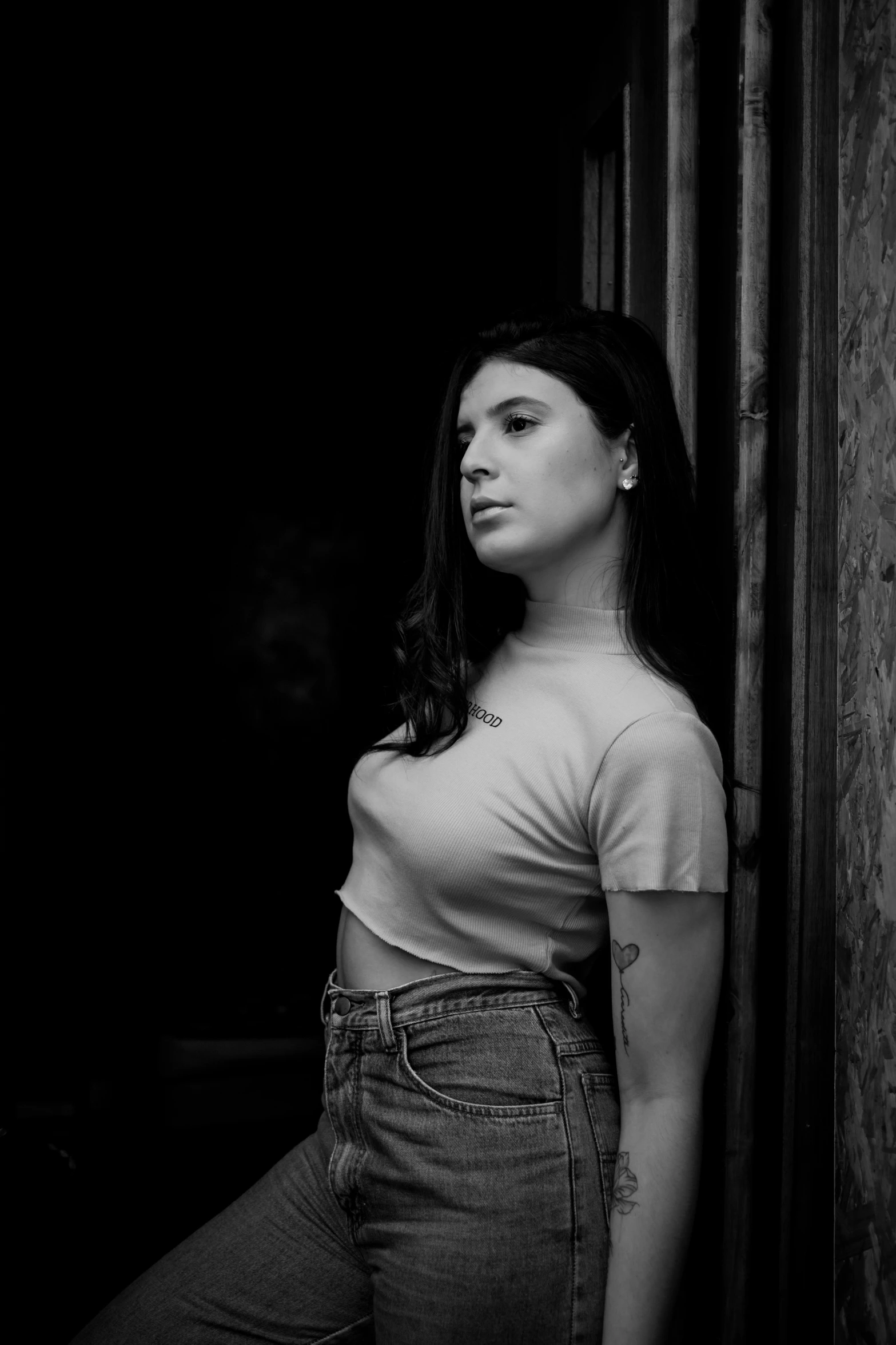 a woman leaning against a wall in a black and white po