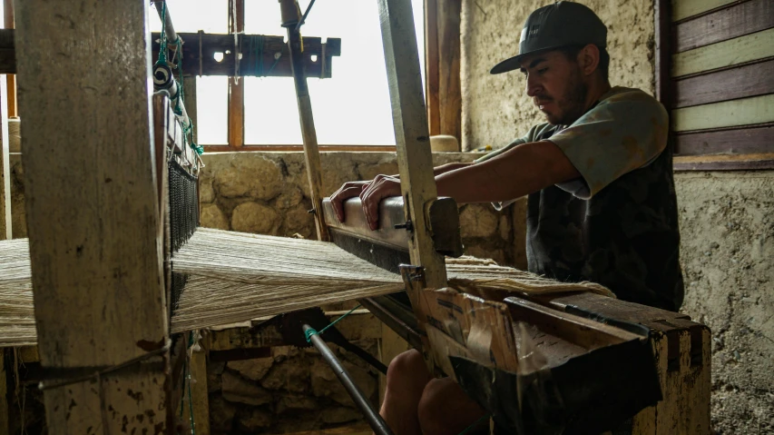 man weaving soing on a machine that is turned upside down