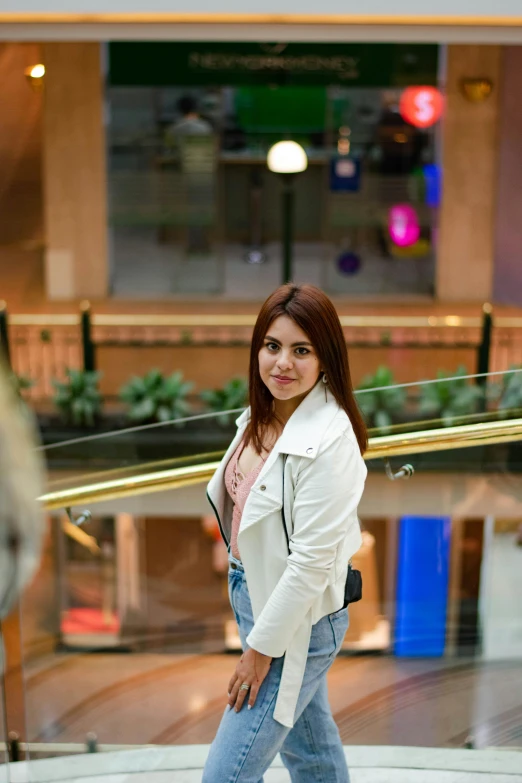 a woman in jeans is holding a rolling suitcase