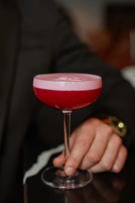 a person holding a glass with red liquid