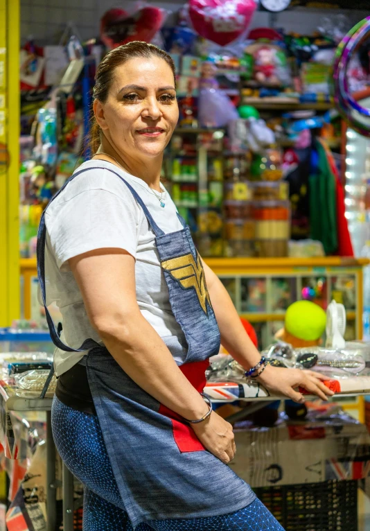 a woman sits at a store table in front of a window