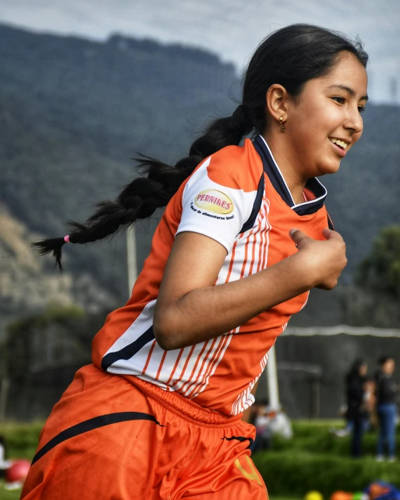 a girl in an orange uniform running by a frisbee