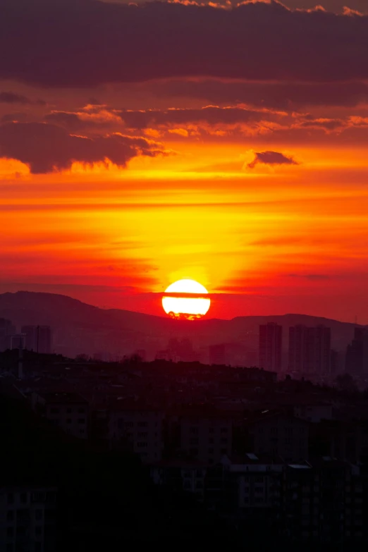 the sun sets over a city with tall buildings