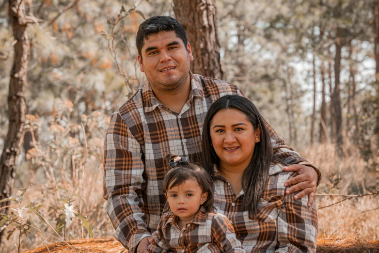 two people and a child are posing in the woods