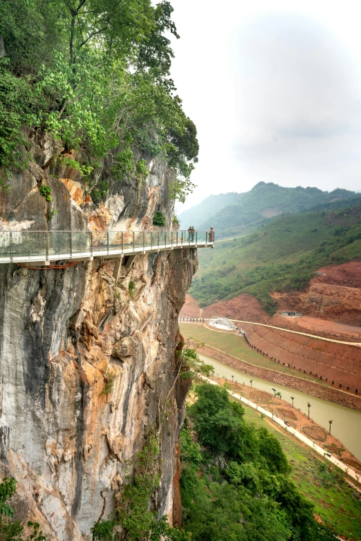 a walkway going along the side of a cliff between two mountains