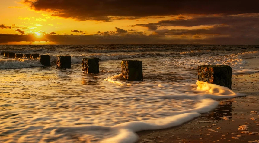 some very pretty water by the shore with a bunch of posts in it