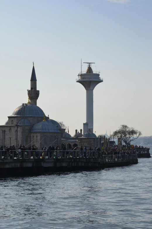 some people are standing on a pier with buildings by the water