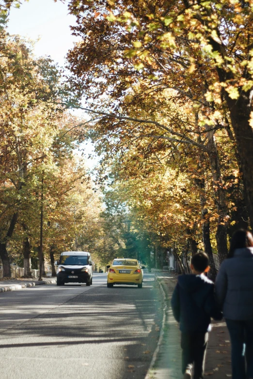 people walking down the sidewalk near some vehicles