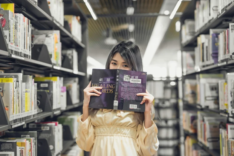 a woman holds two large books over her face