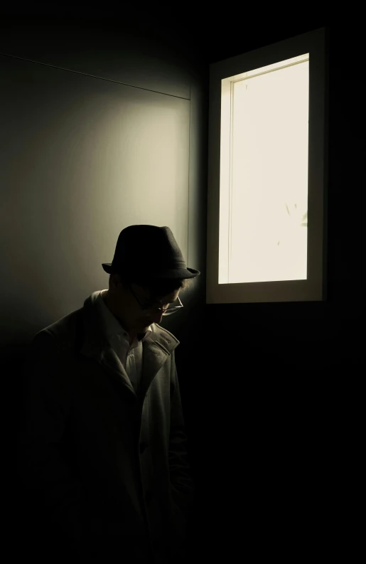 a person wearing a hat stands next to a window