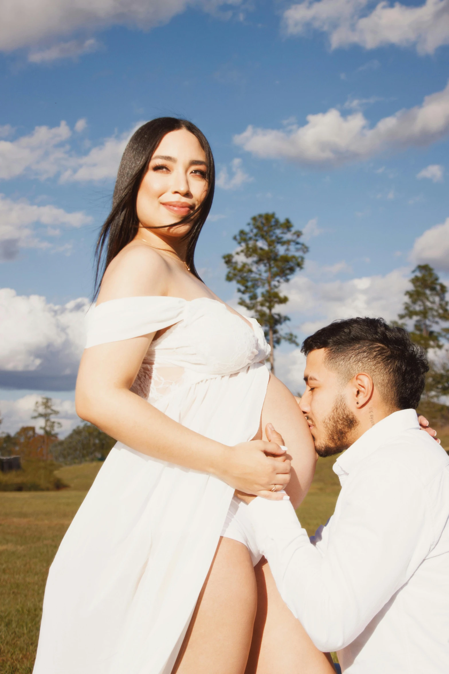 a pregnant woman wearing a long white gown poses for a portrait