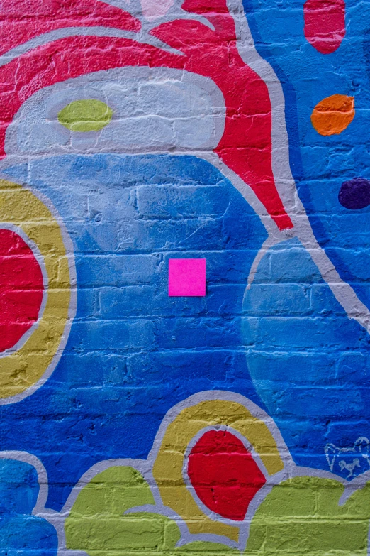 colorful paint and squares on a brick wall