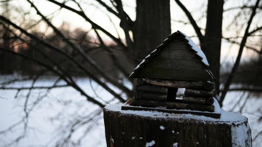 a wooden fence post with a small house on top