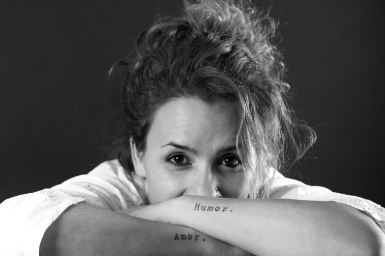 a beautiful young lady with tattooed arms looking at the camera