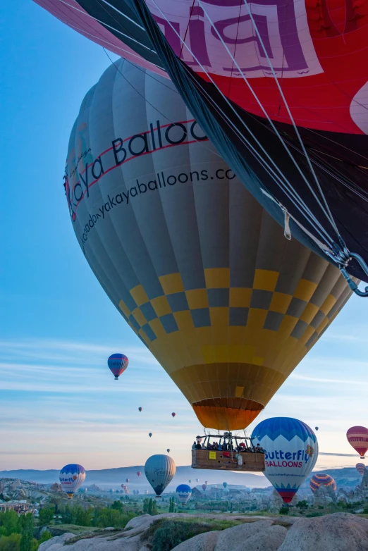 a number of balloons flying in the sky above a hill