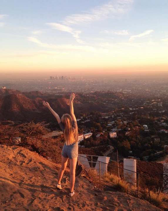 there is a girl standing on top of the mountain