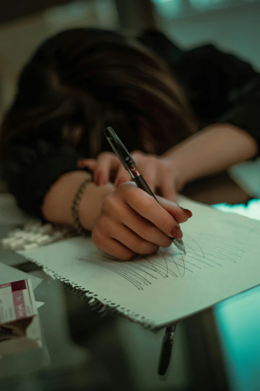 a woman's hand holding a pen writing on a note pad