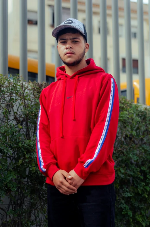 a young man is wearing a red hooded sweatshirt with blue and white stripes