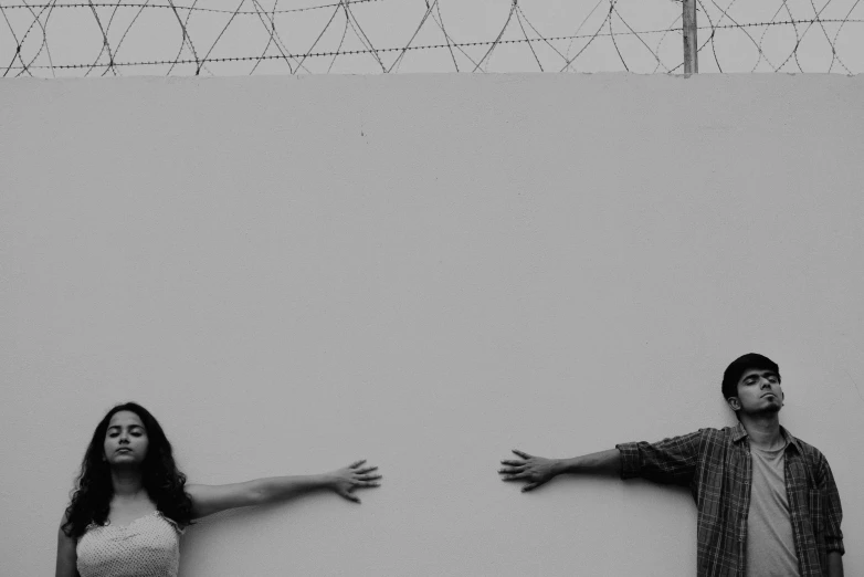 a man and a woman standing next to a wall with wires