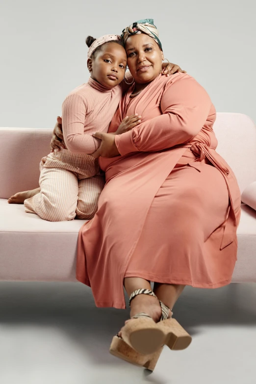 two women emcing on a pink couch