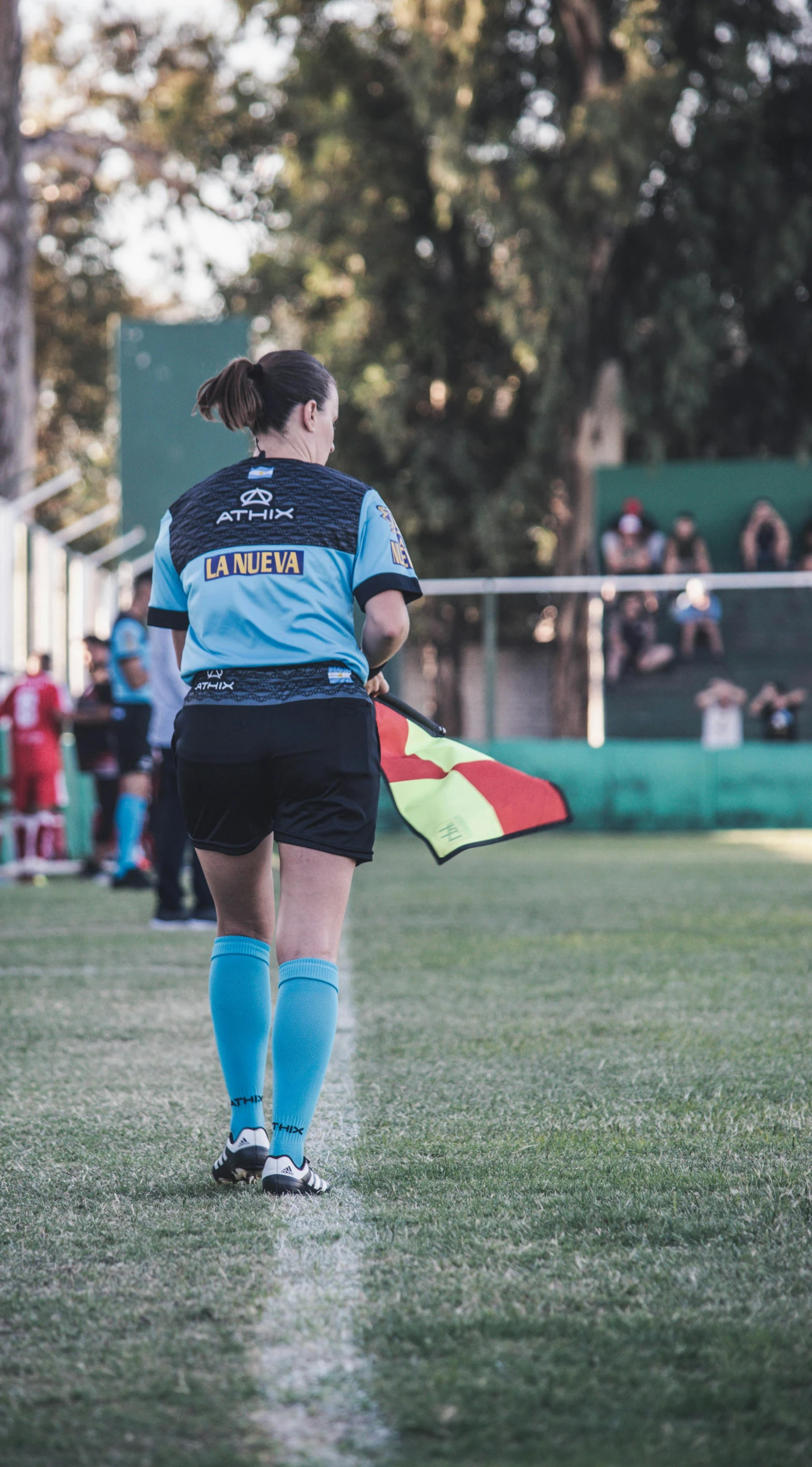 a woman in a black soccer uniform is walking on the field