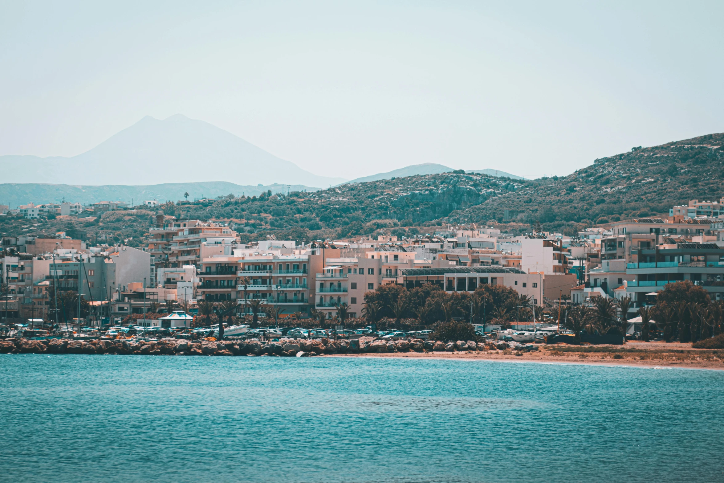 a cityscape with cars parked along the water