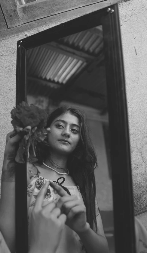 a woman standing looking out from the window with a bouquet of flowers on her shoulder