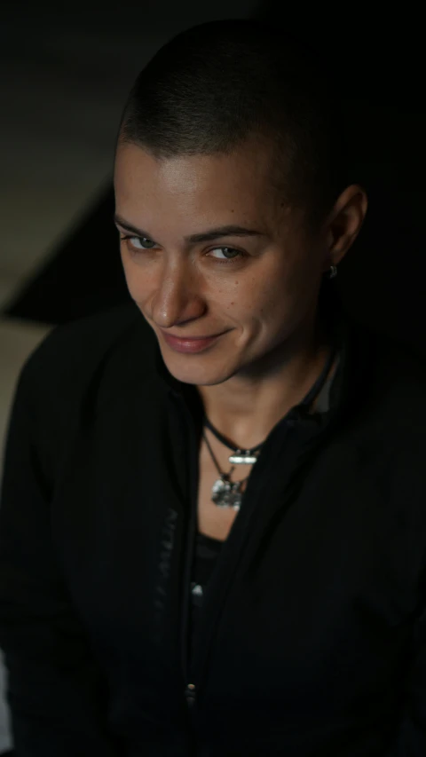 a girl with a shaved head smiles at the camera