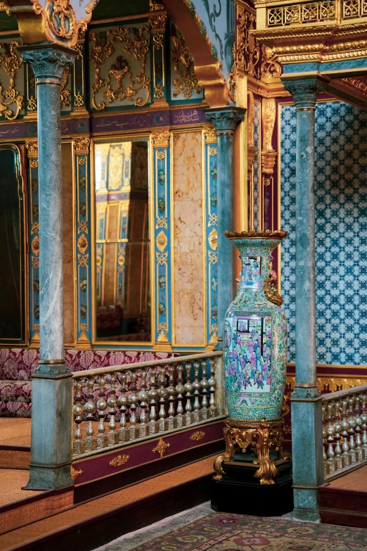 a tall blue and gold vase is in a room with ornate decor