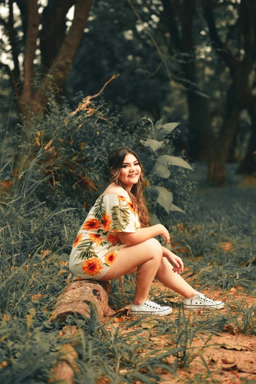 a woman sitting on a log in the middle of a forest