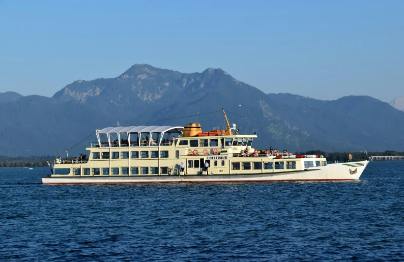 a large white boat on top of a lake next to mountains