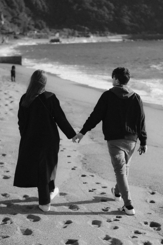 a couple holding hands as they walk down the beach