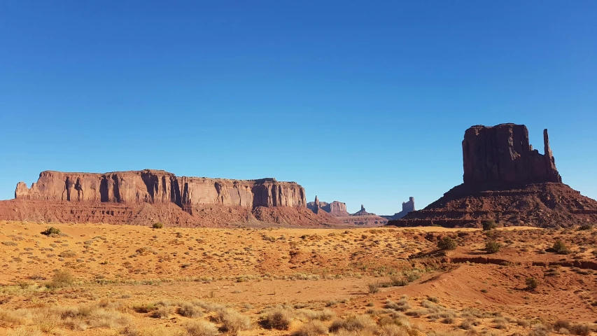 a desert with rock formations and sand and grass