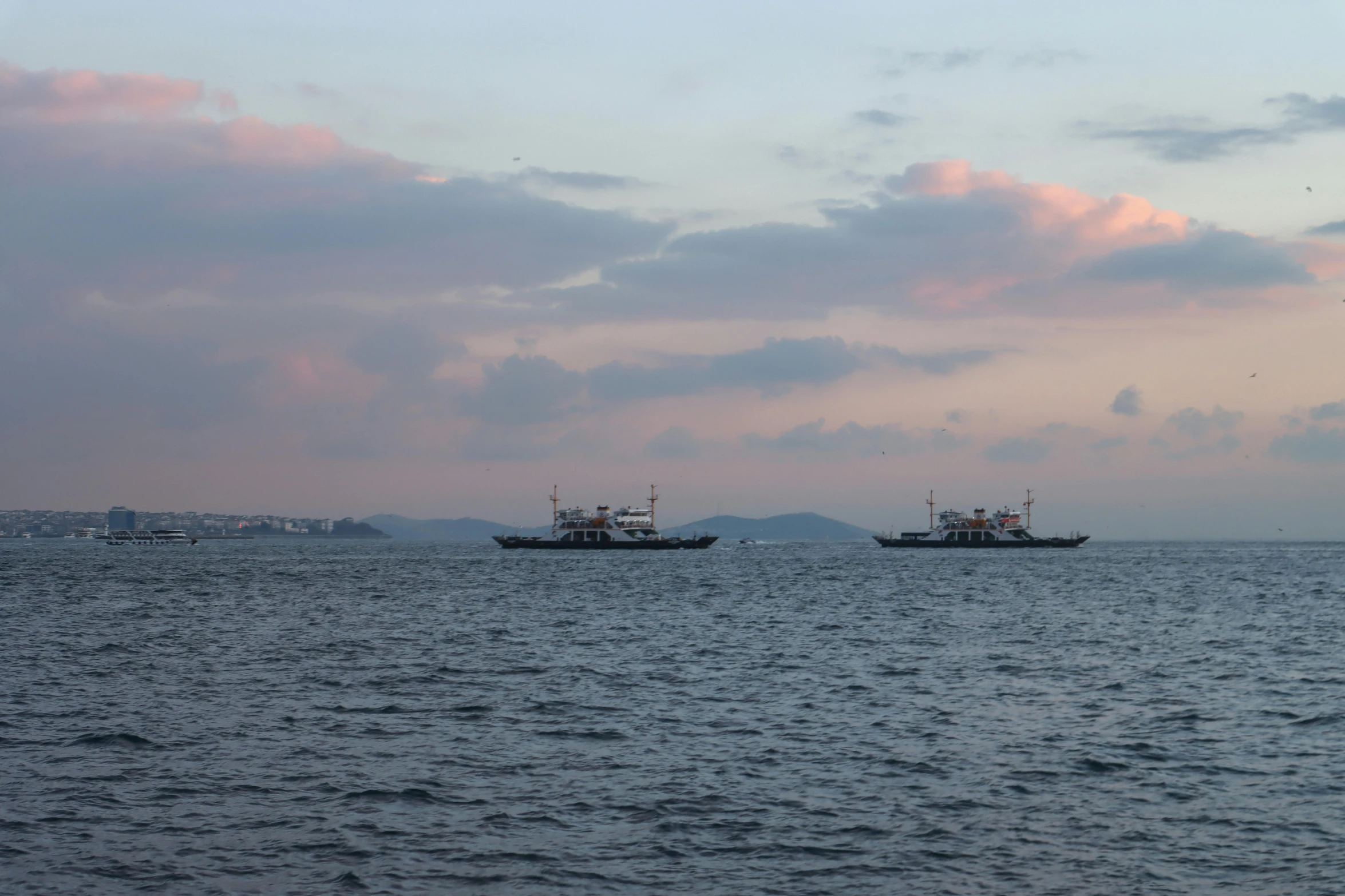 two ships sail through the ocean on a cloudy day