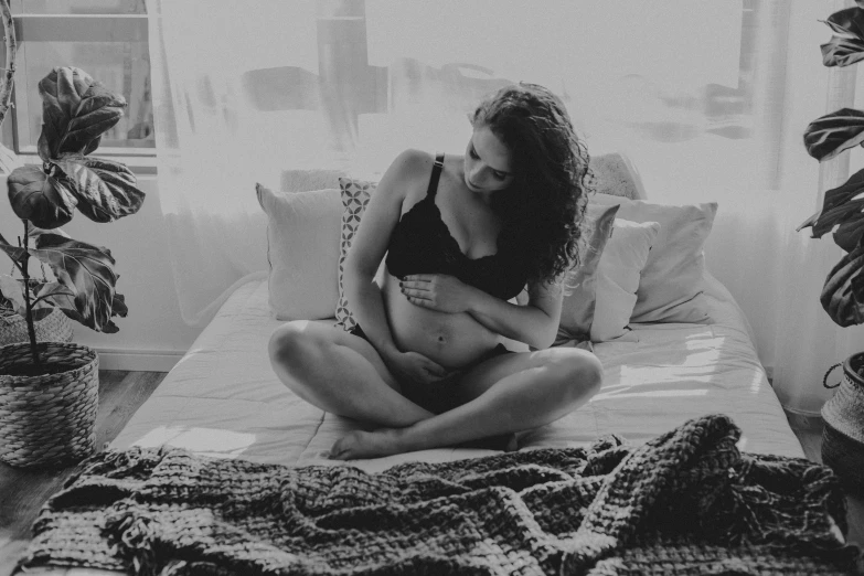 a pregnant girl on the bed in a black tank top