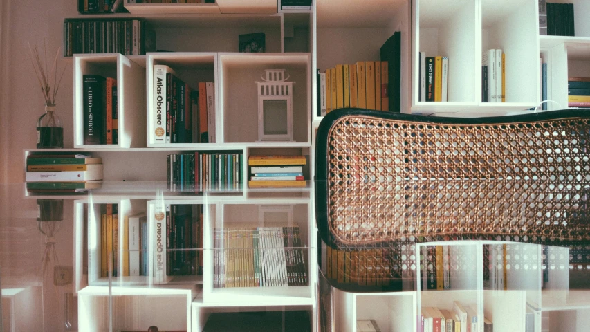 a woven chair sits in front of shelves that have books on them