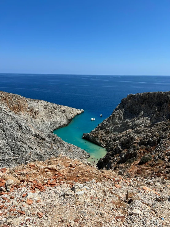 an open space with some blue water sitting on a rocky hillside