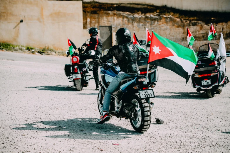 a motorcycle on the road with a group of men and flags behind