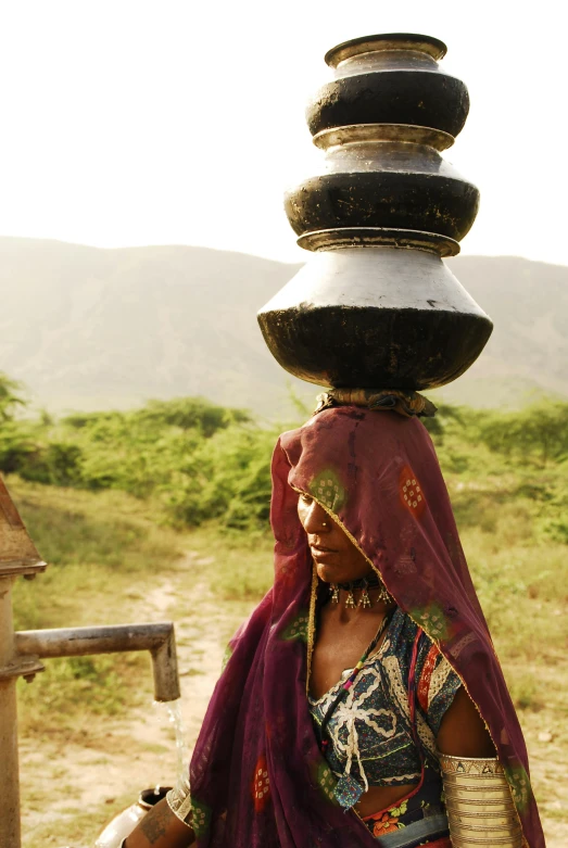 a woman in a red shawl with two stacked plates on her head