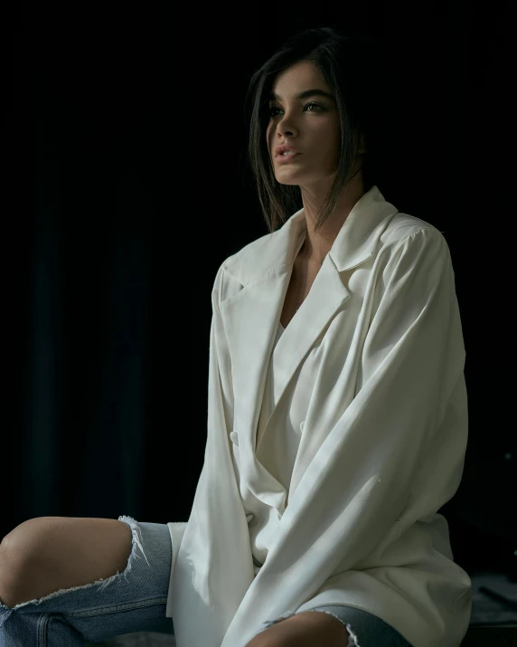 a woman sitting on a floor wearing a white coat