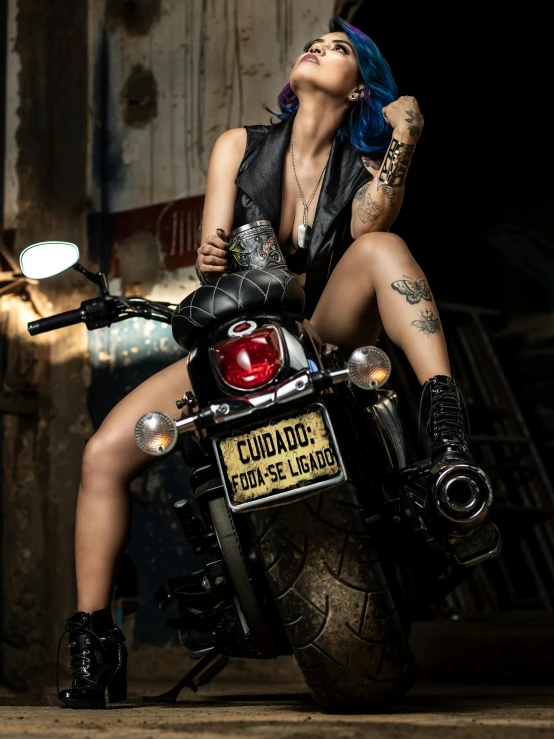 a woman in black with blue hair sitting on a motorcycle