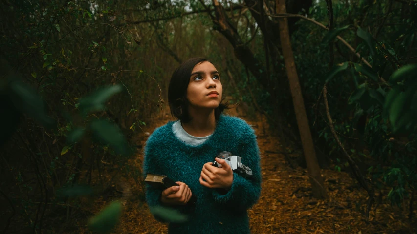 a woman with a camera standing in a forest