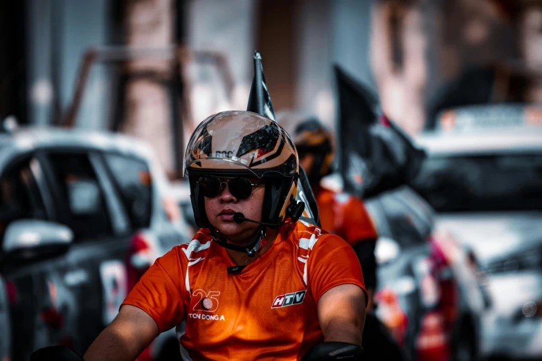 the man is wearing an orange shirt and helmet on a motor bike